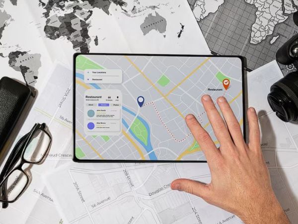 Hand interacting with tablet map showing route and location pins business directory